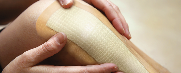 Hands holding a bandaged on a person's knee