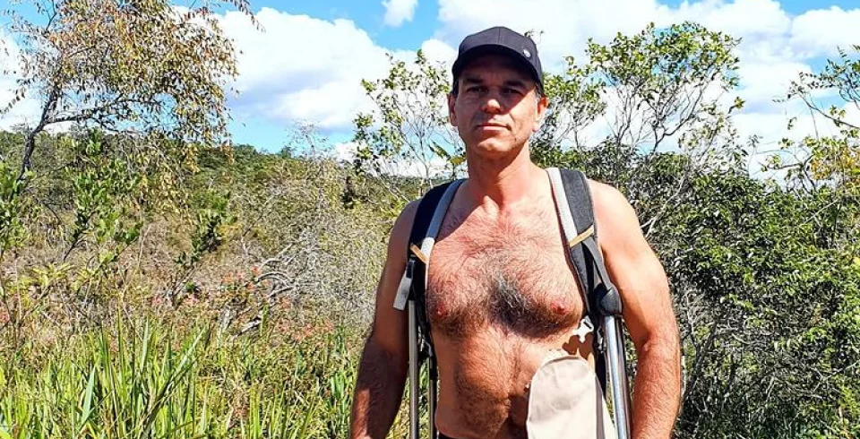 a man with a backpack and a hat standing in a field