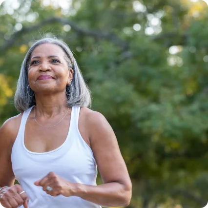 Una mujer con una cara sonriente en medio de un entorno verde natural.